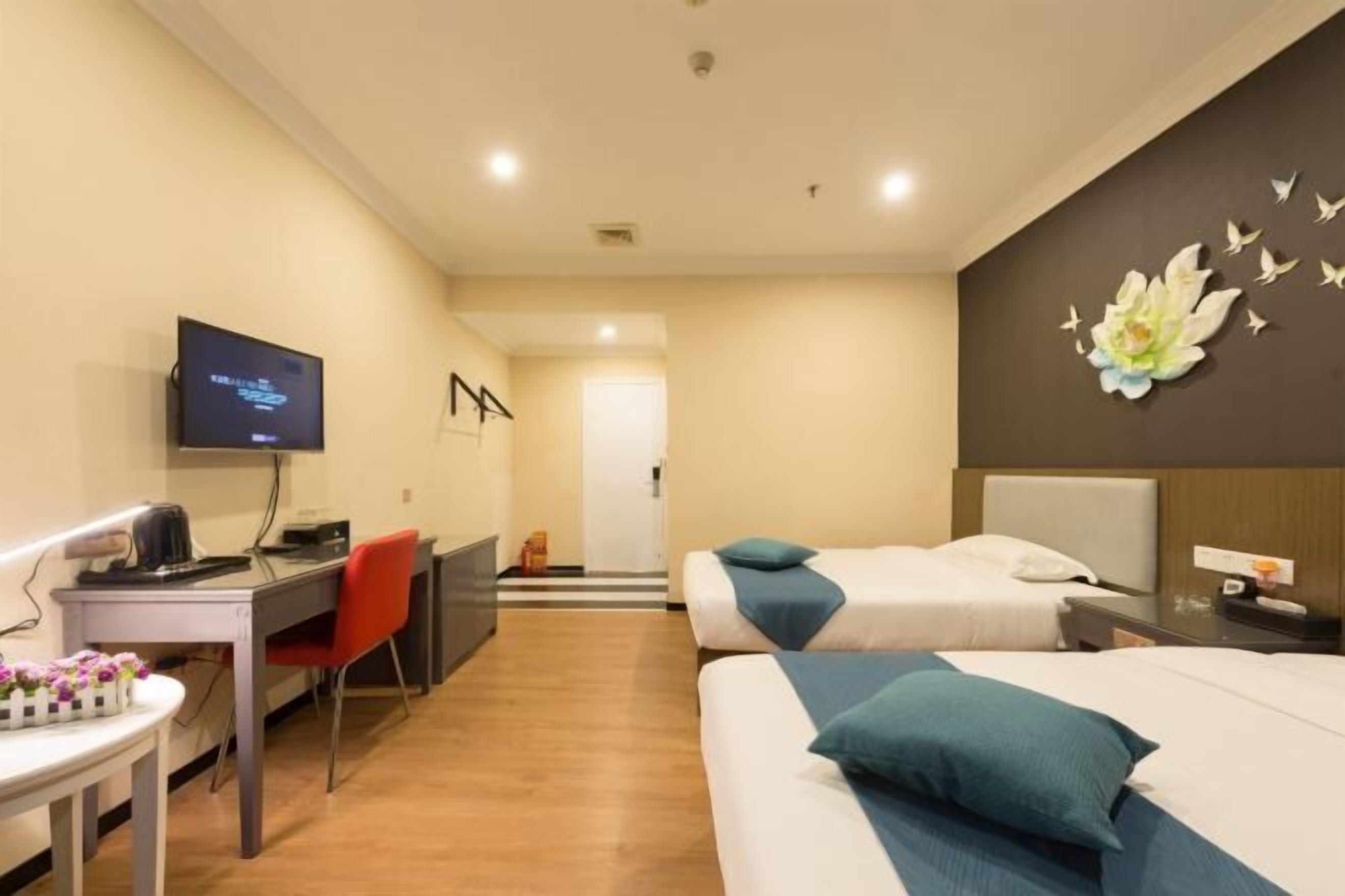 A hotel room with two beds, a desk with a chair, a television, and a wall decoration.