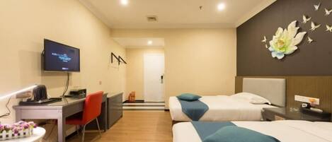 A hotel room with two beds, a desk with a chair, a television, and a wall decoration.