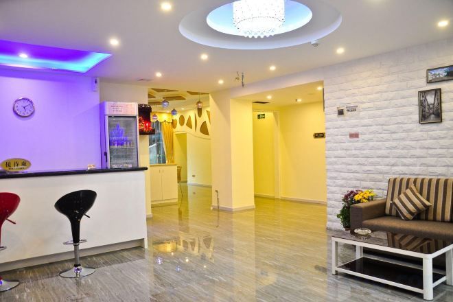 A hotel lobby with a reception desk, bar stools, a sofa, and a coffee table.
