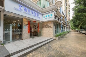 Un hotel con fachada moderna, amplios ventanales de vidrio y una entrada con textura de piedra.