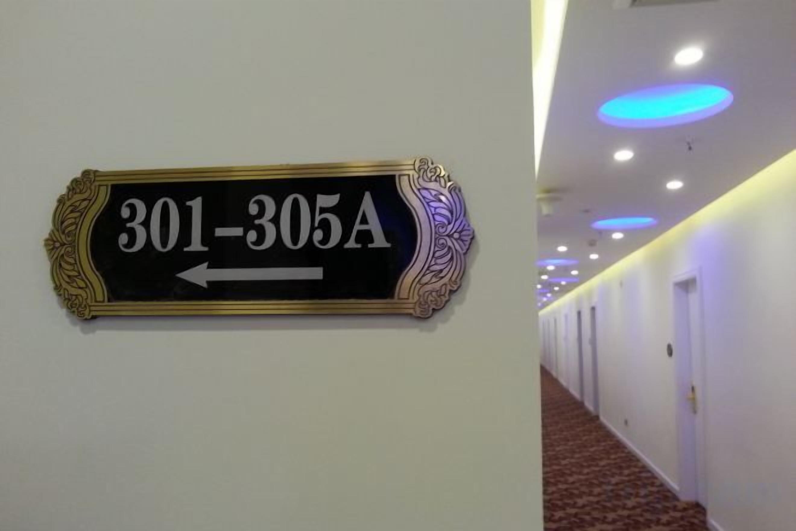Un pasillo con un cartel de indicaciones que muestra los números de habitación 301-305A, apuntando a la izquierda.