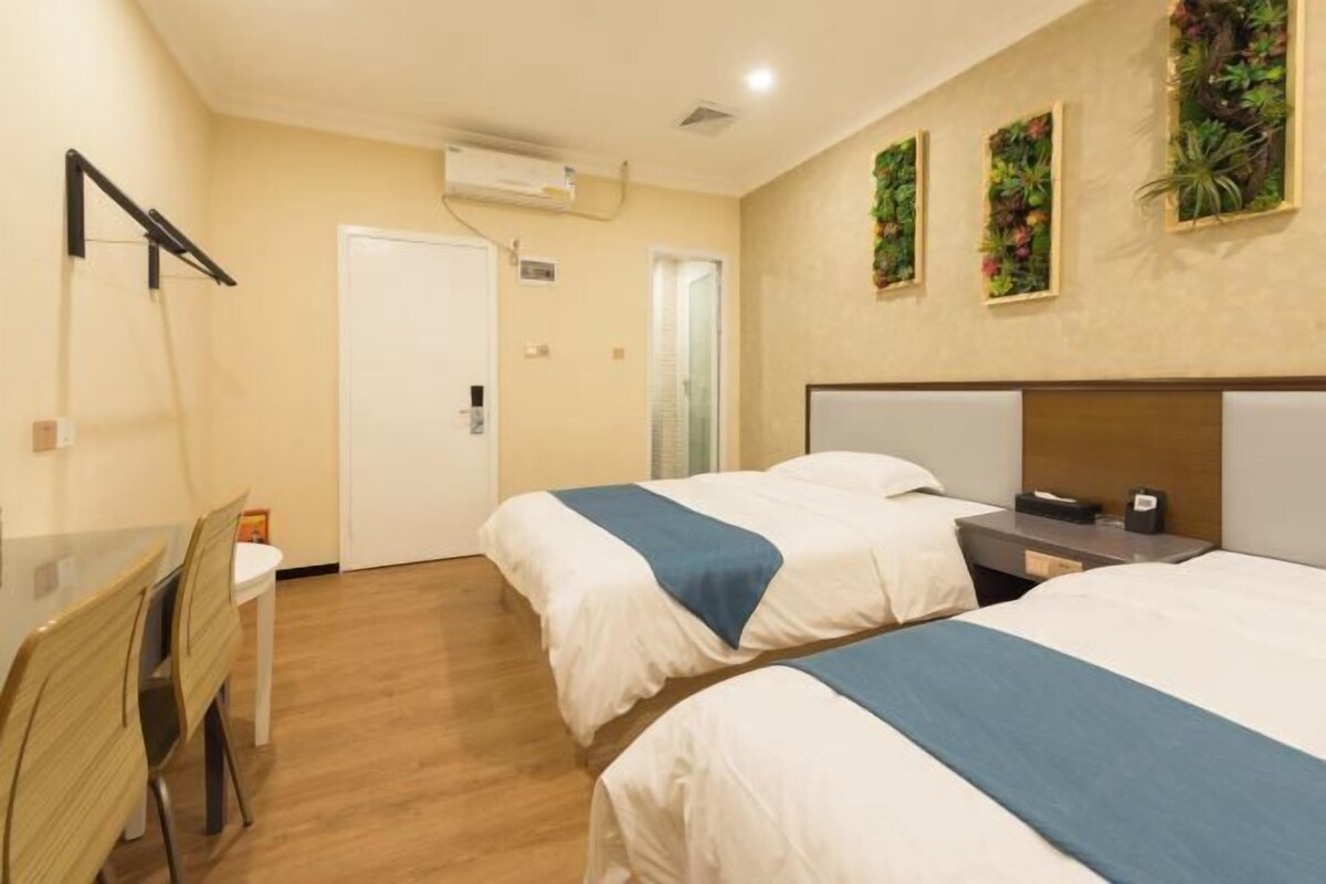 Una habitación de hotel con dos camas, un escritorio, una silla y una puerta.