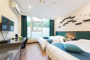 Una habitación de hotel con dos camas, un escritorio, un televisor y un ventanal grande.