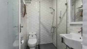 Un baño pequeño con inodoro, ducha envuelta en vidrio y lavamanos.