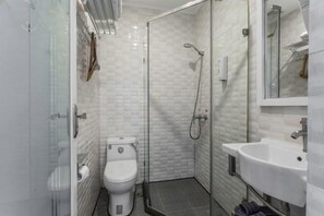 Un baño pequeño con inodoro, ducha envuelta en vidrio y lavamanos.