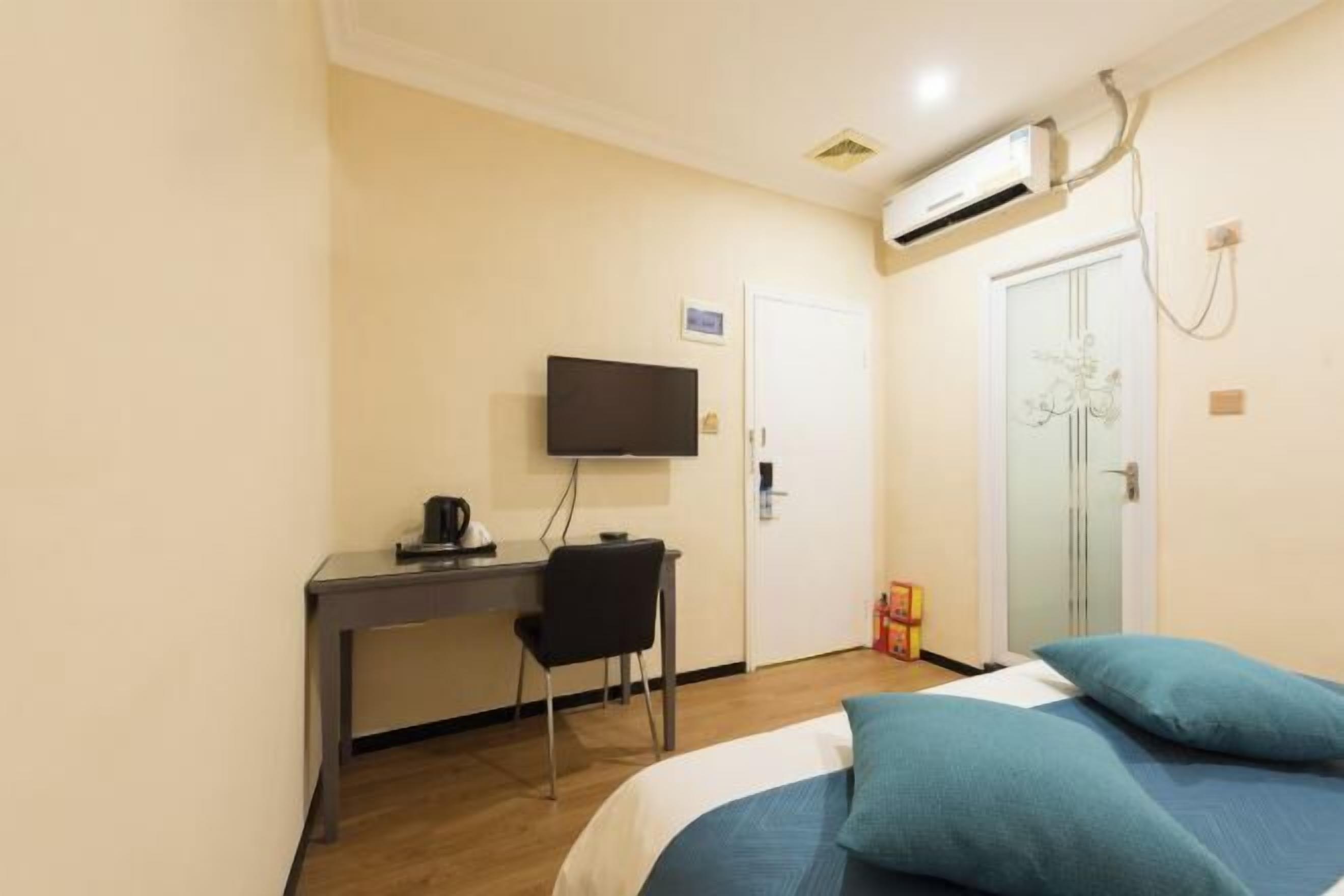 Une chambre d’hôtel équipée d’un lit, d’un bureau avec une chaise, d’une télévision et d’un appareil de climatisation.