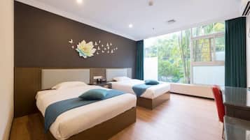 Habitación de hotel con dos camas, un escritorio, una silla y vista a zonas verdes.
