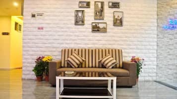 A lobby with a sofa and coffee table, a white brick wall, and framed pictures.