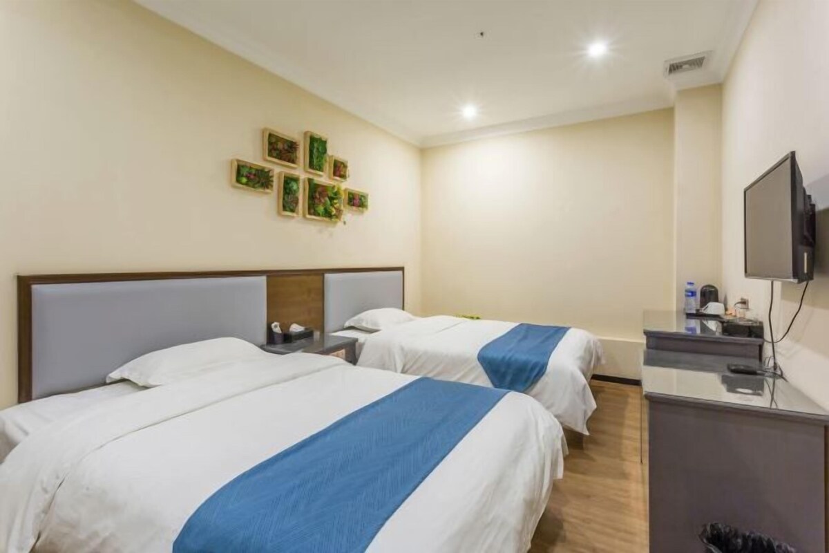 Habitación de hotel con dos camas, un escritorio, un televisor y una pequeña kitchenette.