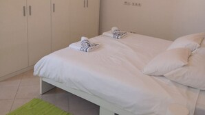 A bedroom with a bed, two towels, a green rug, a bedside table with a lamp, and a wardrobe. - Apartment Marta (Rab)