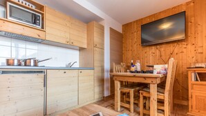 Una cocina compacta con armarios de madera, microondas y comedor con mesa y sillas.