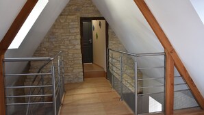 A narrow staircase with metal railings leading to a stone wall and a door.