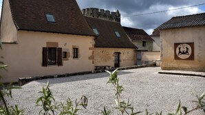 A courtyard with stone buildings, a small wooden bench, and a sign with a logo.