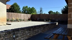 A courtyard with a stone wall, gravel area, and a wooden bench.