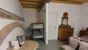 Ett rum med ett träpanelat tak, ett runt bord med stolar, en byrå och en dörr.