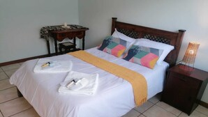 A neatly made bed with white linens, a yellow throw blanket, and two towels folded on the bed. - 6 Sleeper self catering house (L'Agulhas)