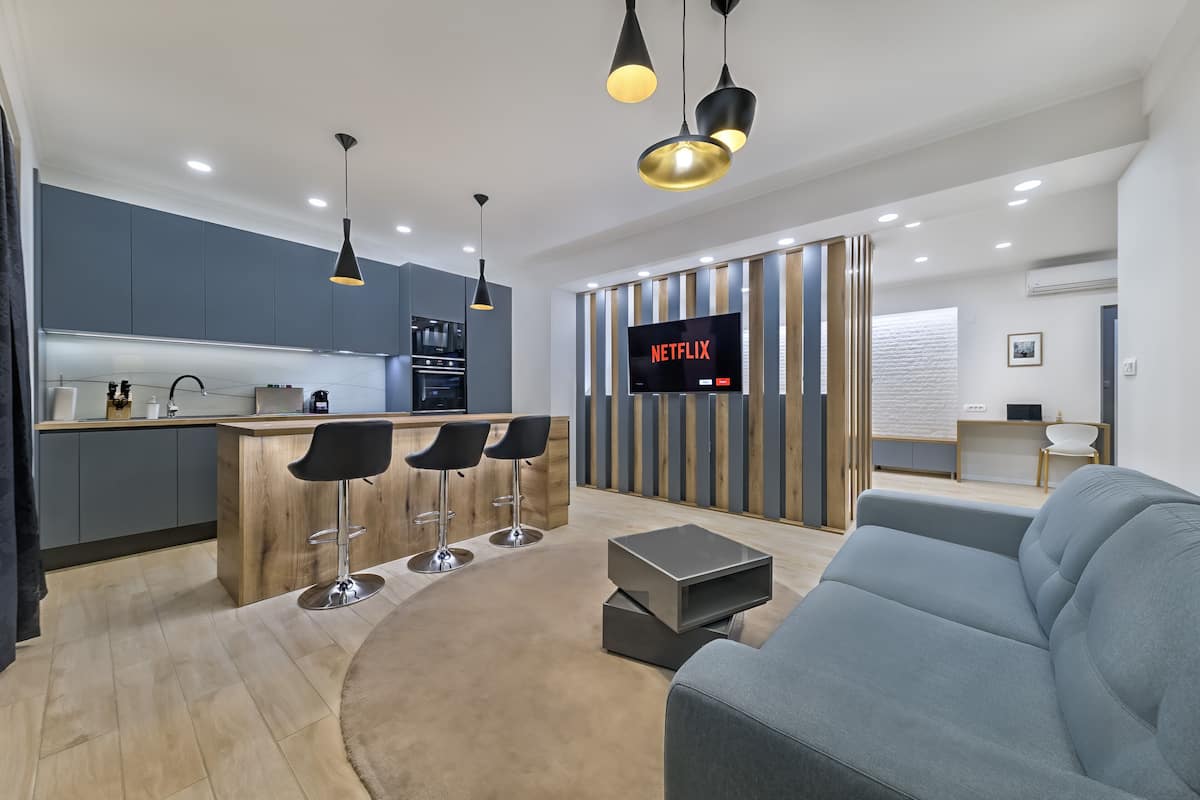 A modern living room with a grey sofa, a coffee table, and a TV displaying 'NETFLIX'.