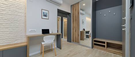 A modern room with a wooden desk, a white chair, a mirror, and a built-in bench.
