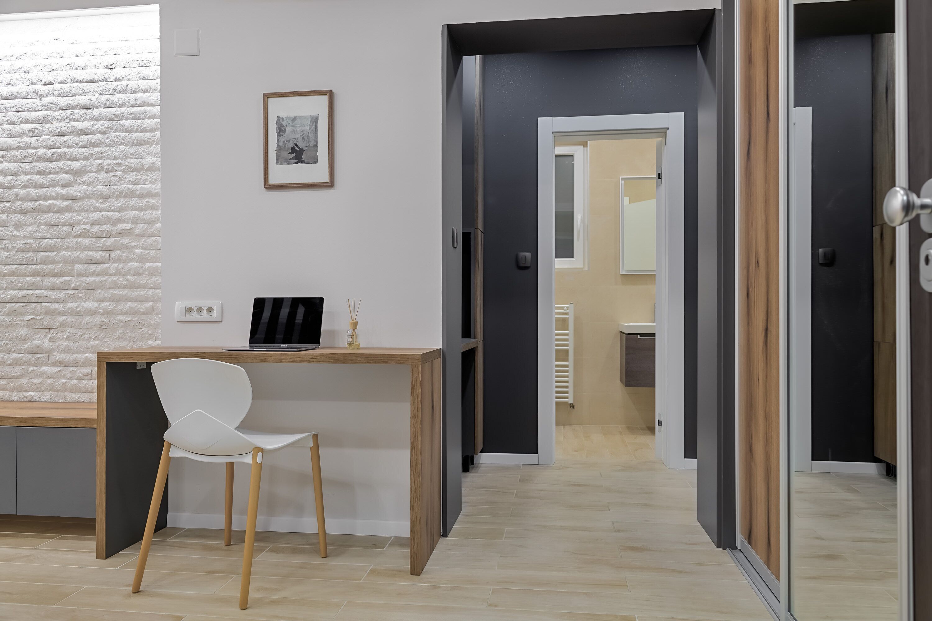 Een moderne kamer met een houten bureau, een witte stoel en een lijst met een foto aan de muur.