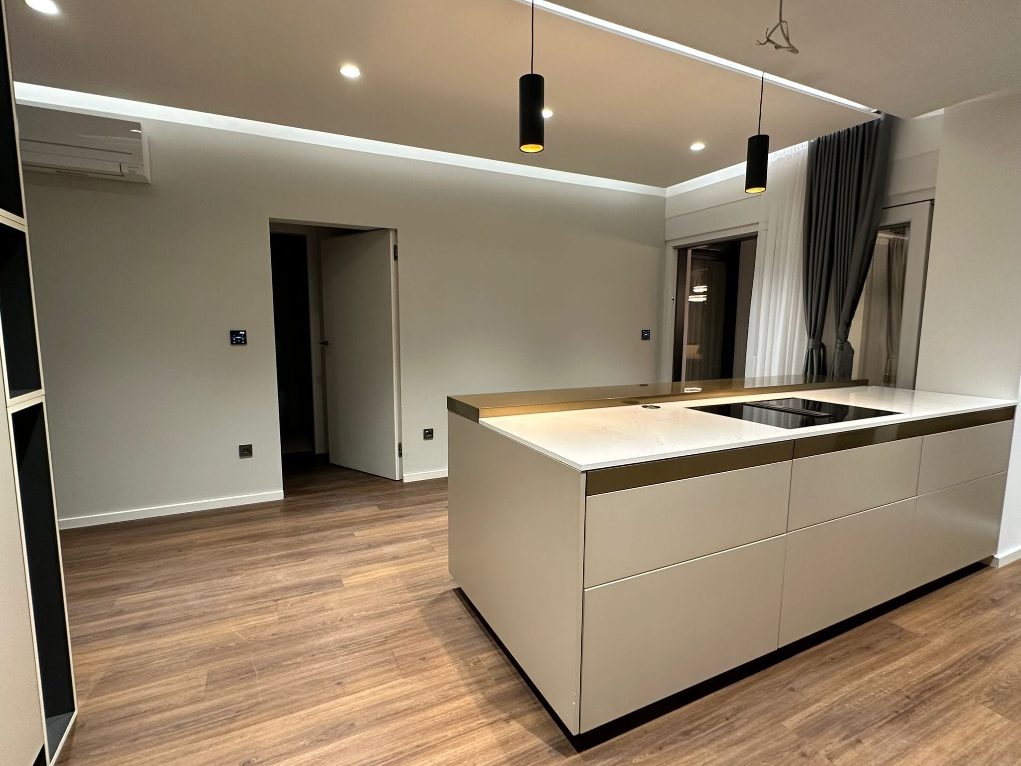 Una cocina moderna con una isla central, iluminación colgante y vista al área de comedor.