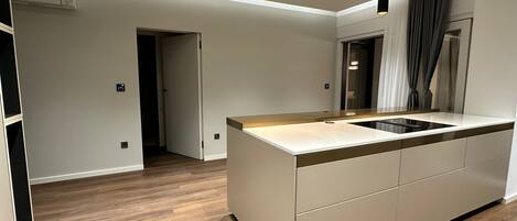 Una cocina moderna con una isla central, iluminación colgante y vista al área de comedor.