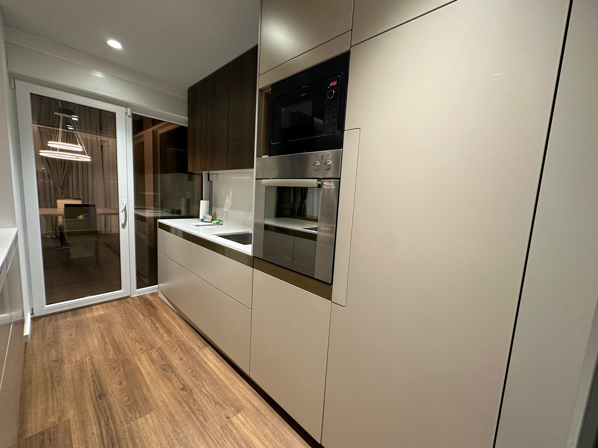 A modern kitchen with a built-in oven, microwave, and a large window.