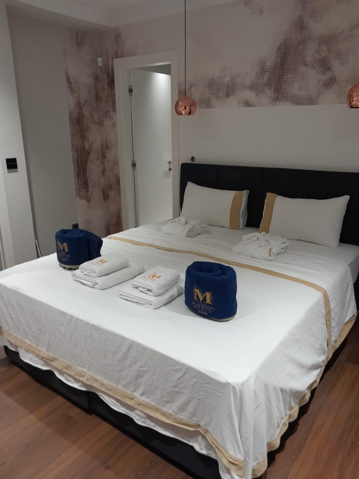 A hotel room with a large bed, white bedding, and two blue towels with a logo.