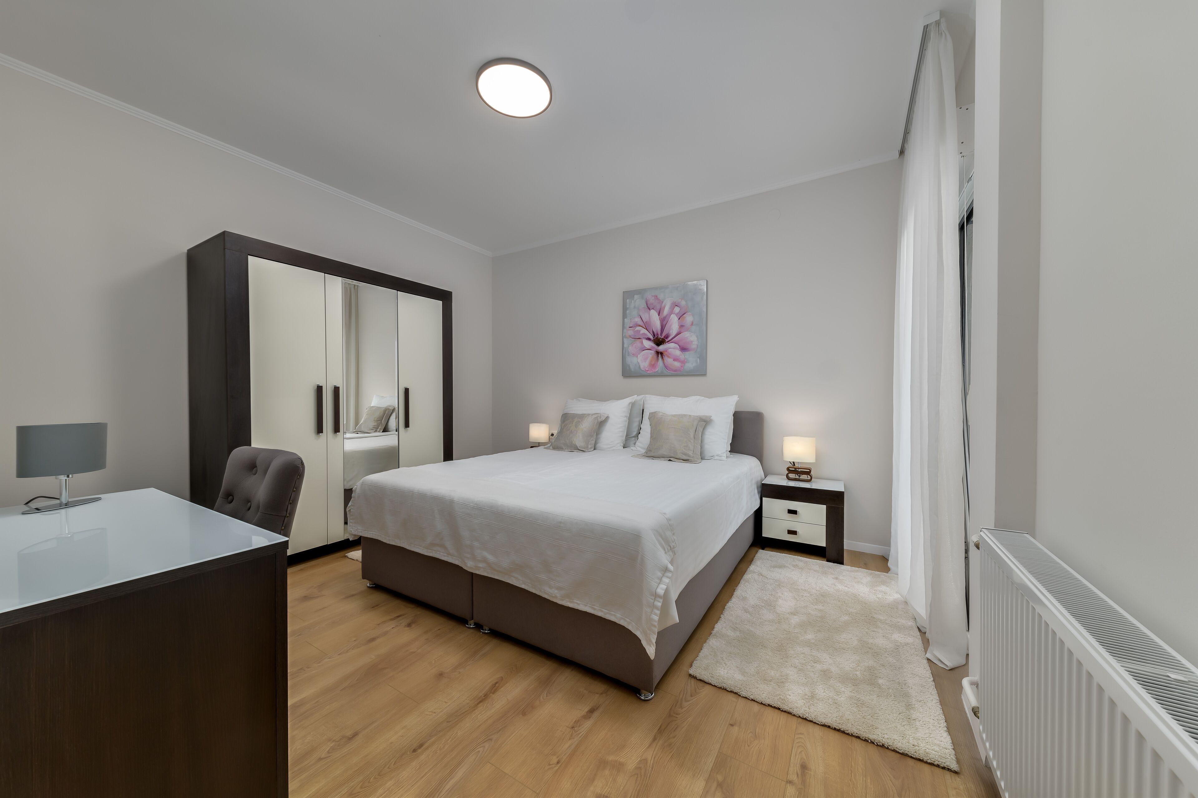 Une chambre à coucher moderne avec un lit, des tables de chevet, un bureau et une armoire.