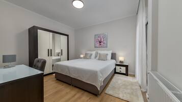 Une chambre à coucher moderne avec un lit, des tables de chevet, un bureau et une armoire.