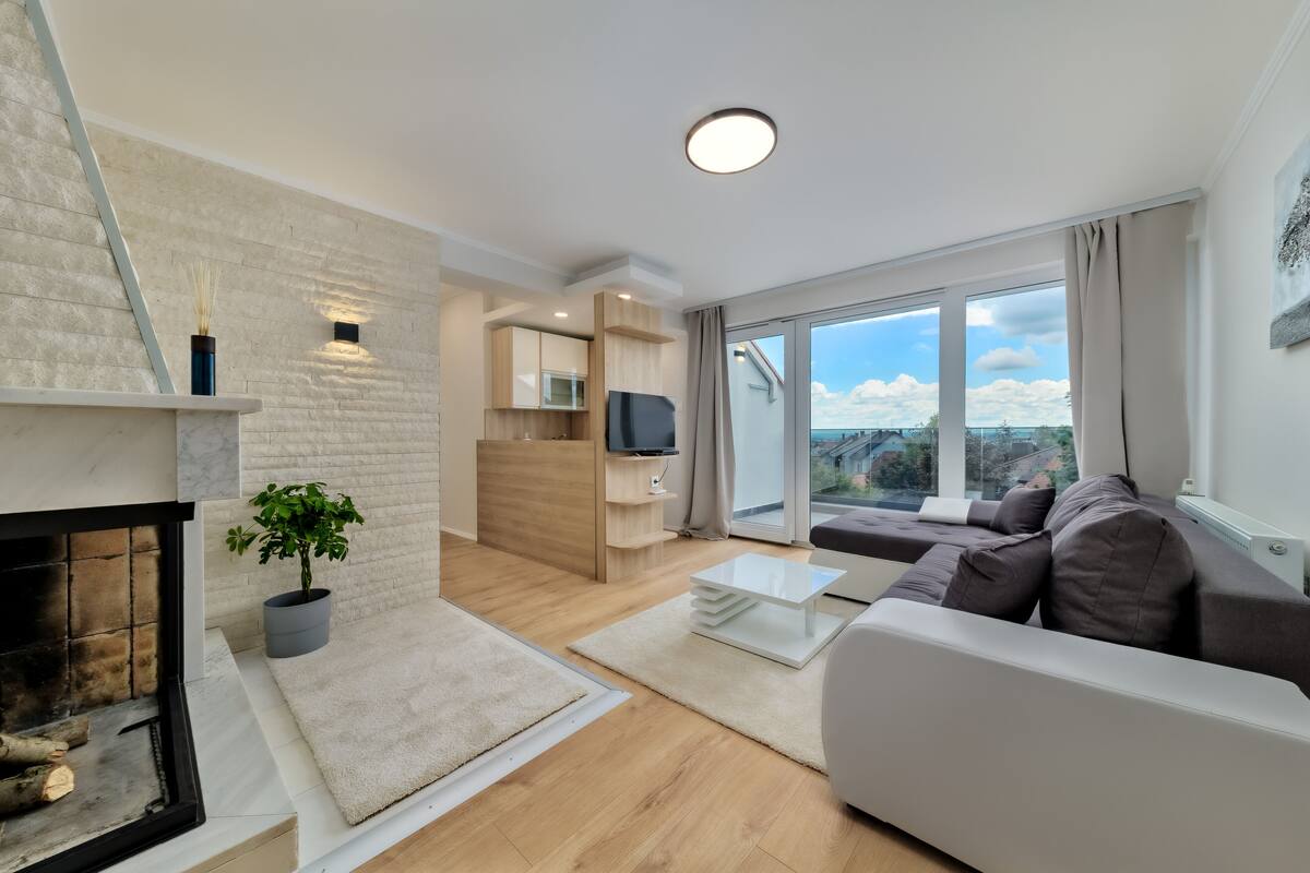 A modern living room with a fireplace, a sofa, a coffee table, and a TV.