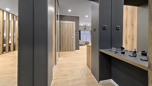 Un pasillo moderno de hotel con piso de madera, paredes grises y un mostrador de recepción de madera con servicios.