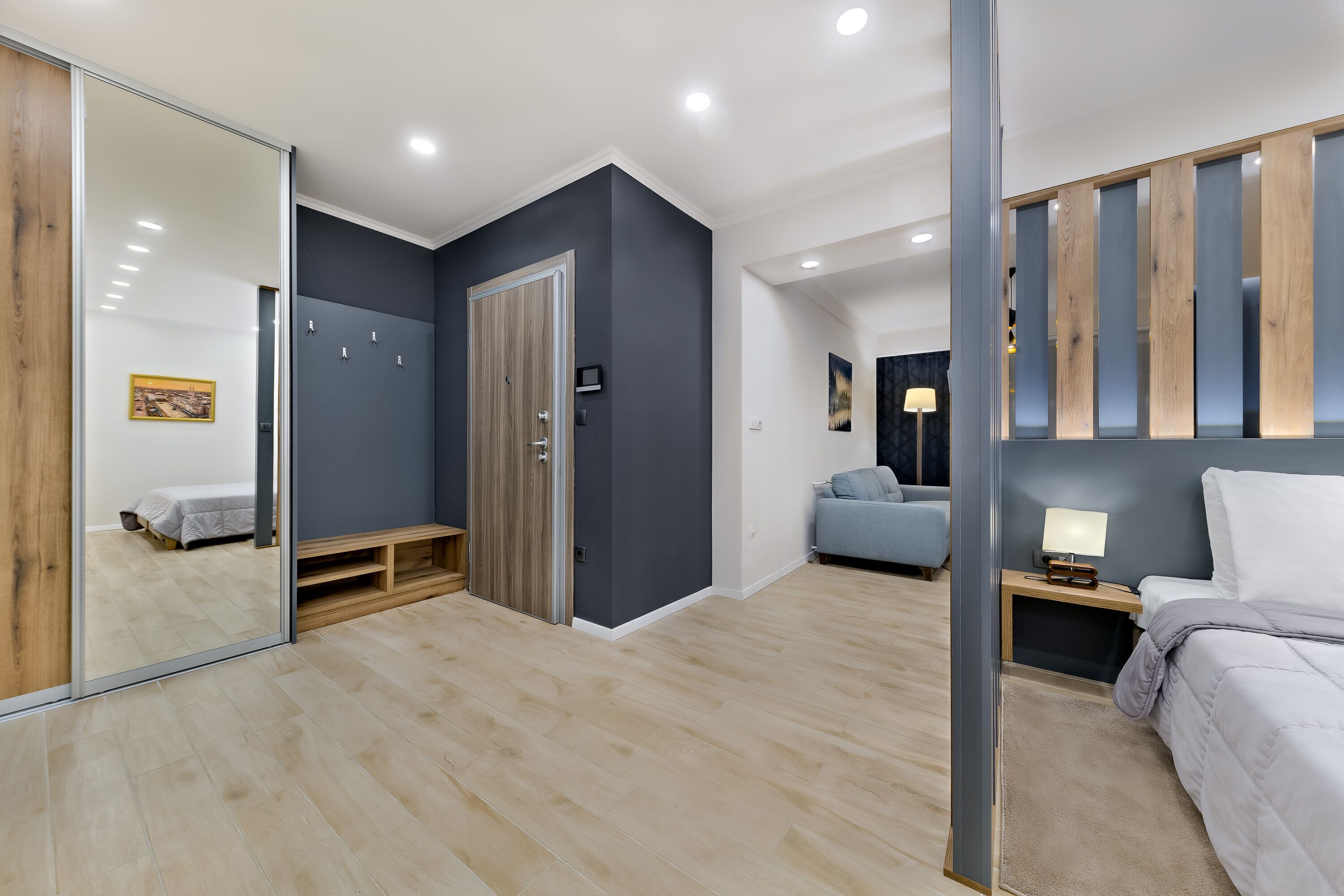 Ein modernes Schlafzimmer mit großem Spiegel, Kleiderschrank, Bett und Nachttisch.
