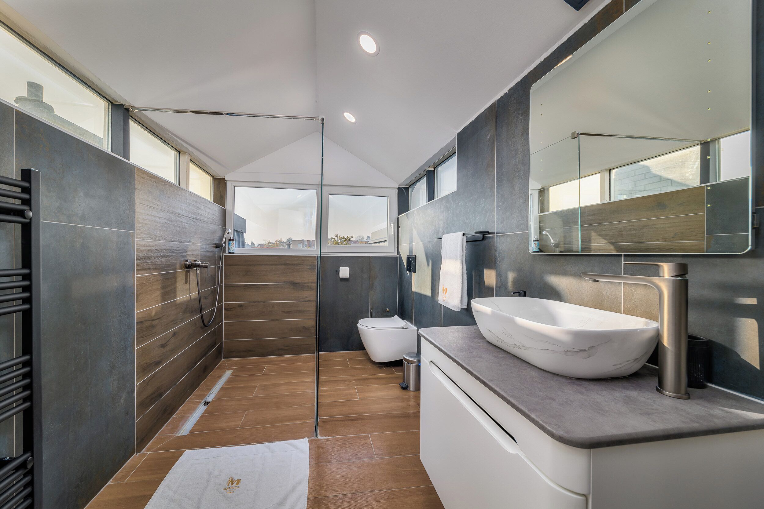Un baño moderno con un espejo grande, un lavamanos sobre encimera y una cabina de ducha con paredes de vidrio.