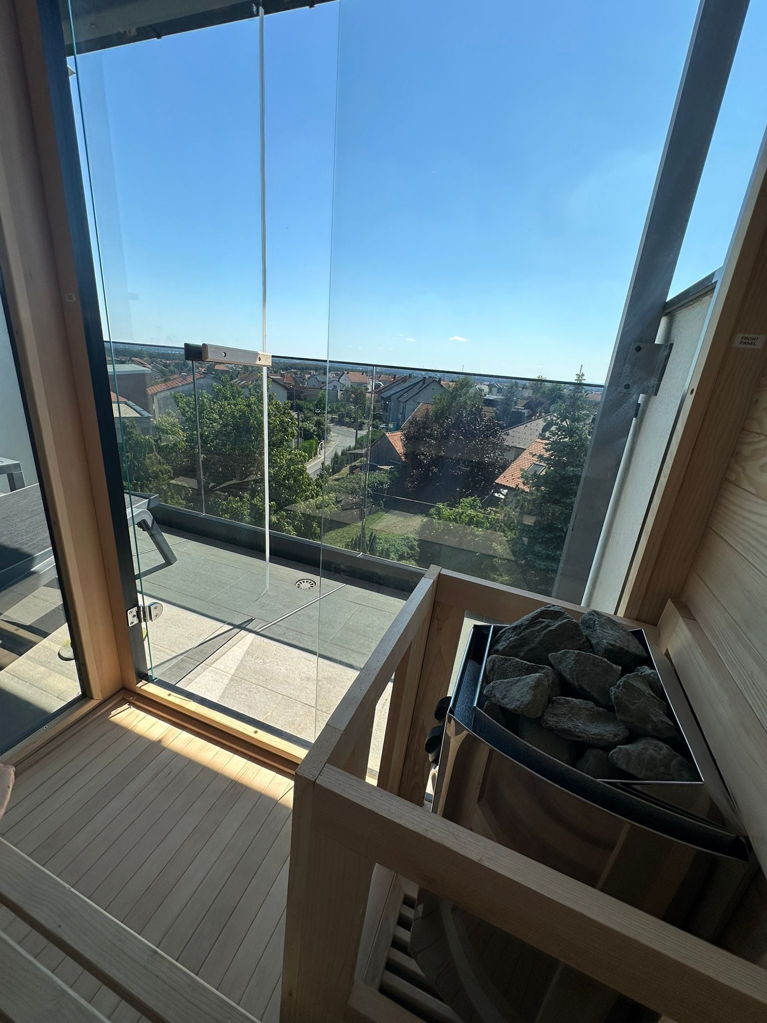 A balcony with a glass door, wooden floor, and a view of a residential area.