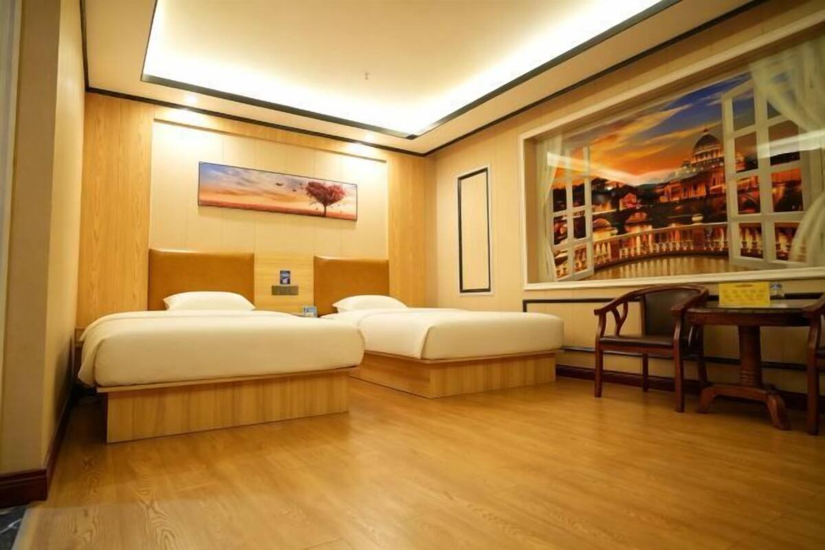 A hotel room with two beds, a desk, and a window with a cityscape view.