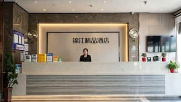 Un mostrador de recepción de hotel con un cartel grande, un reloj y una pantalla de televisión.