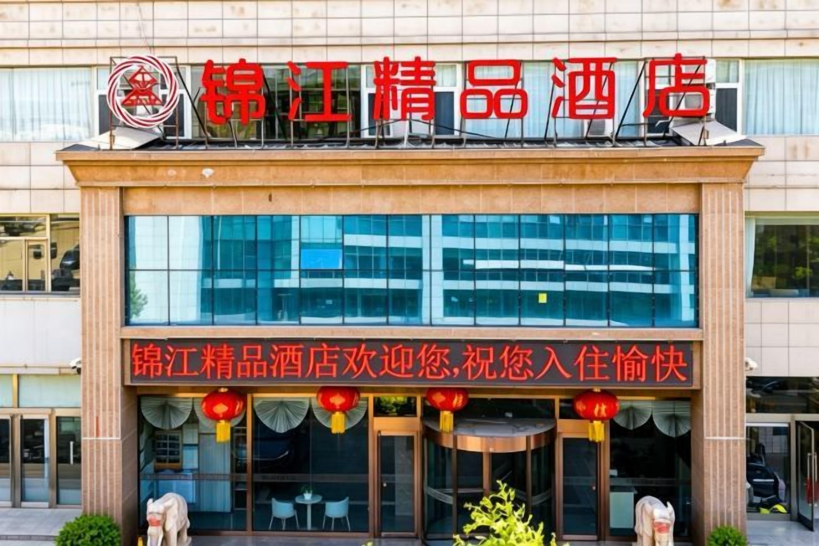 A hotel entrance with a signboard and a glass facade.