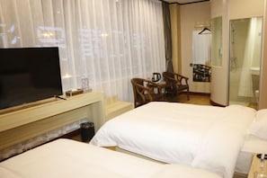 A hotel room with a large flat-screen TV, a wooden desk, two single beds, a chair, a mirror, and a shower area. - Xinjinjiang Boutique Hotel (Dai County)