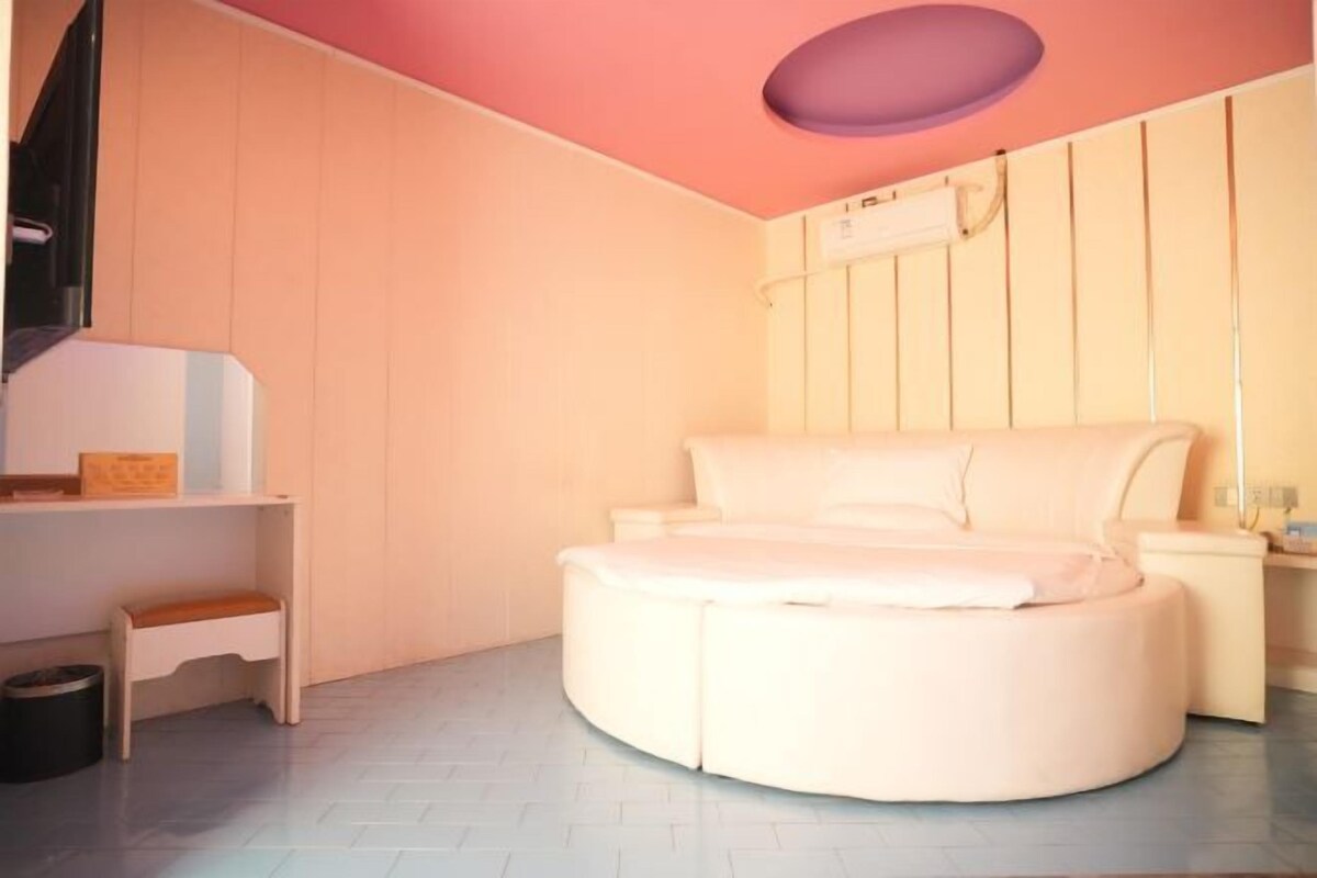 A circular bed in a room with a wooden wall and a ceiling light fixture.