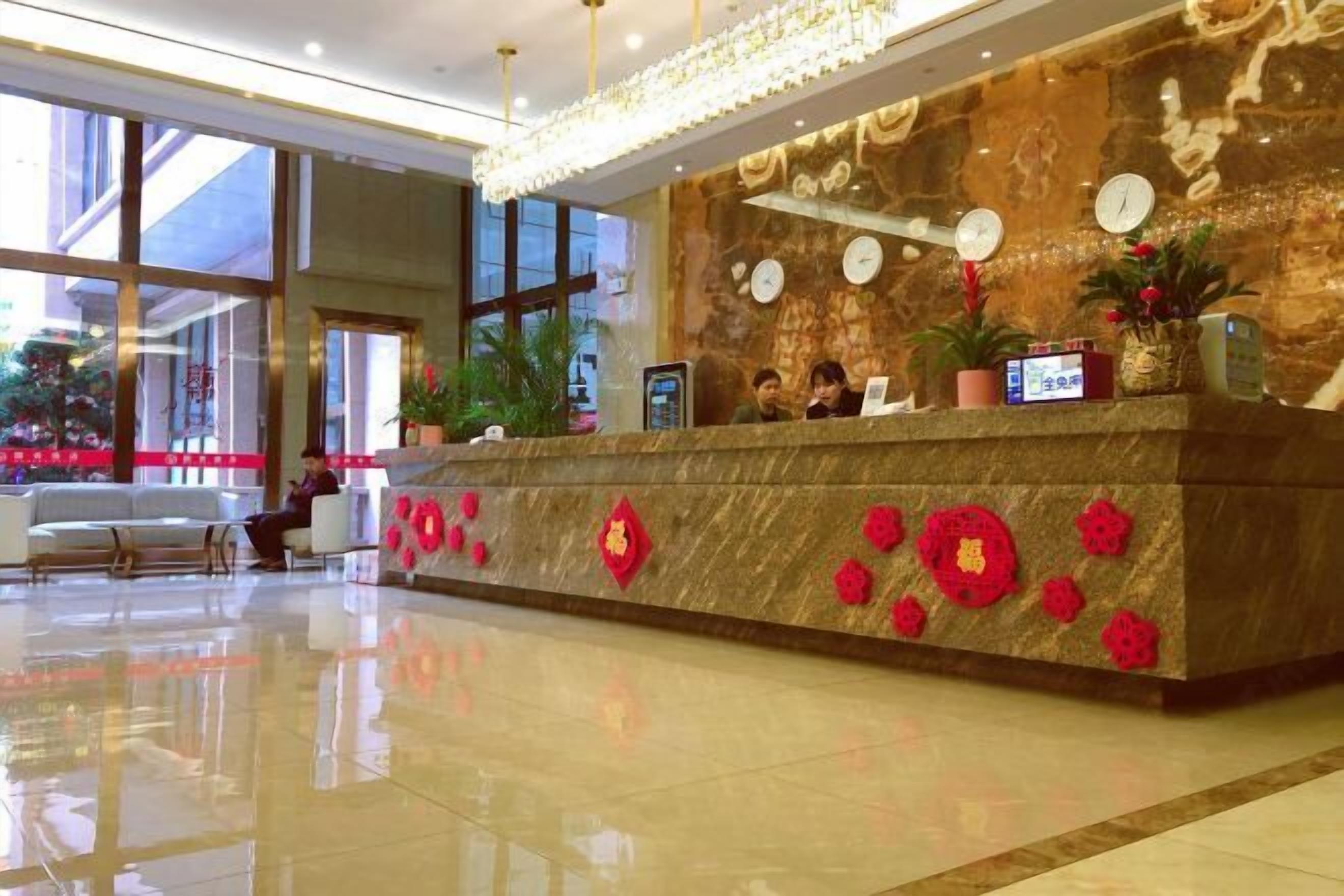 A hotel reception area with a marble counter, clocks, and decorative elements.