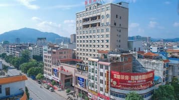A multi-story hotel with a prominent sign on the building, surrounded by other buildings and a clear sky.