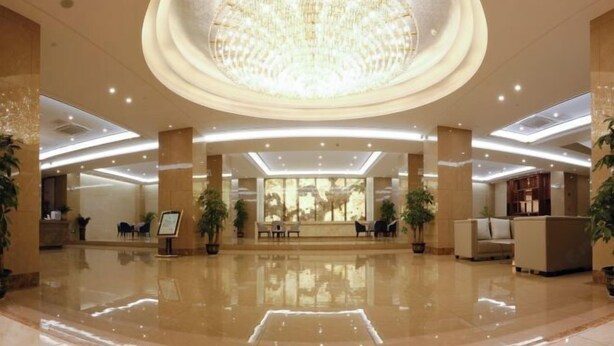 A spacious lobby with a large chandelier, seating areas, and potted plants. - Guoken Hotel (Cenxi)