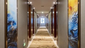 A long, narrow hallway with a patterned carpet and artwork on the walls. - Guoken Hotel (Cenxi)