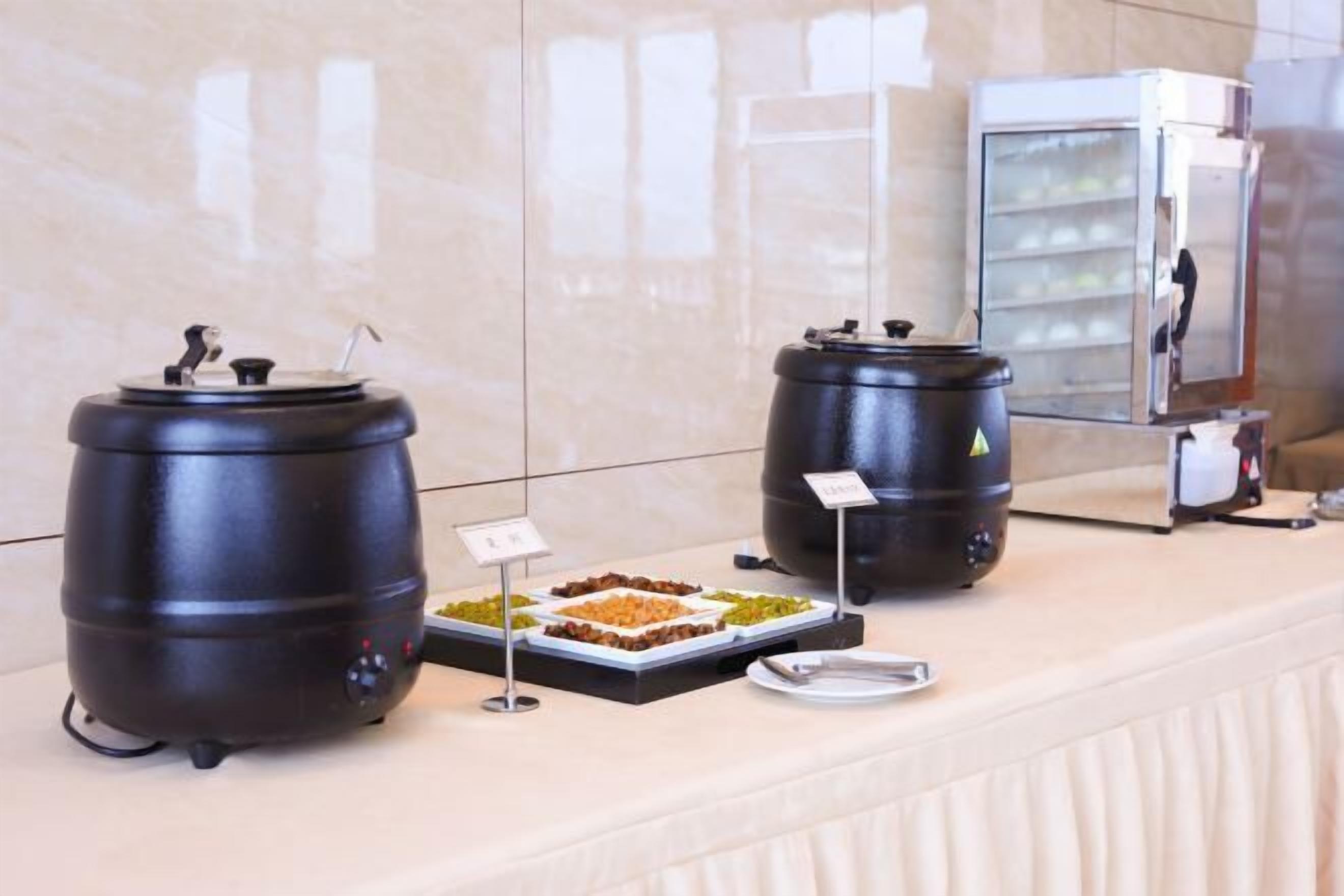 A buffet setup with two large black containers, a refrigerated display case, and a tray of food.