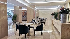 A hotel lobby with a reception desk, seating area with tables and chairs, and potted plants. - Guoken Hotel (Cenxi)