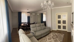Relax in this stylish living room with a large sofa, dining area, and elegant rug.
