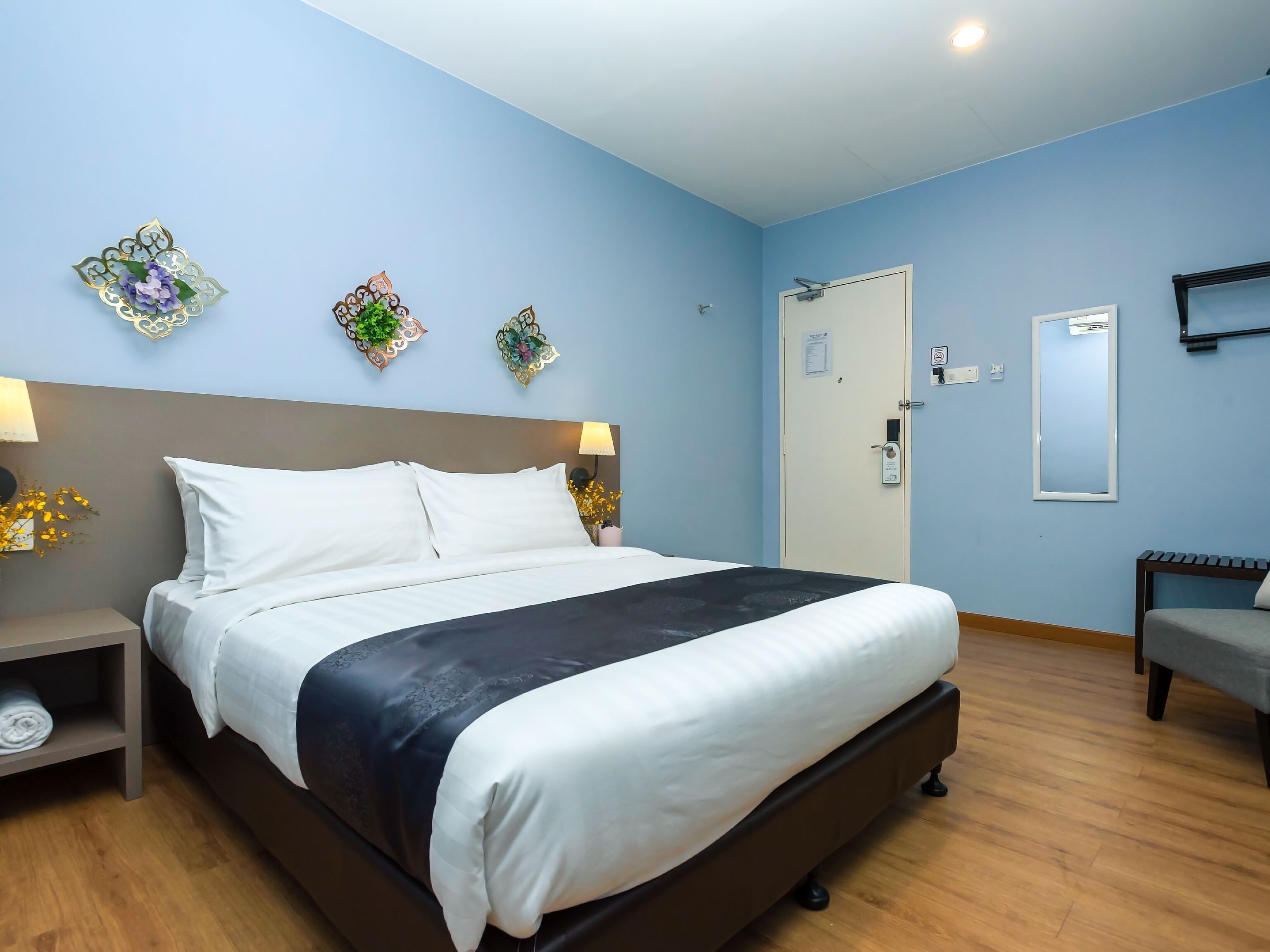 Une chambre d’hôtel bien rangée, avec un lit, des tables de chevet, un bureau et une chaise.