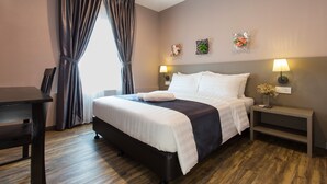 Una habitación de hotel ordenada con cama, mesitas de noche, escritorio y ventana con cortinas.