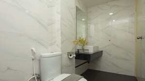 Un baño moderno con inodoro, ducha de mano, lavabo y espejo.