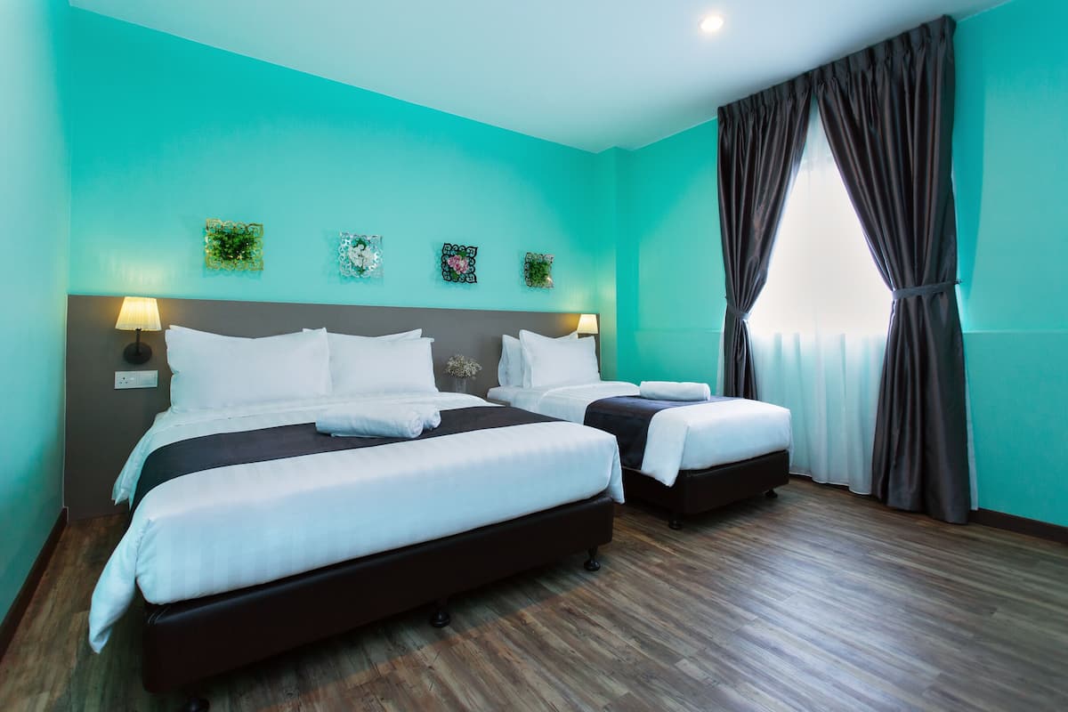 A hotel room with two beds, teal walls, wooden flooring, and decorative wall art.